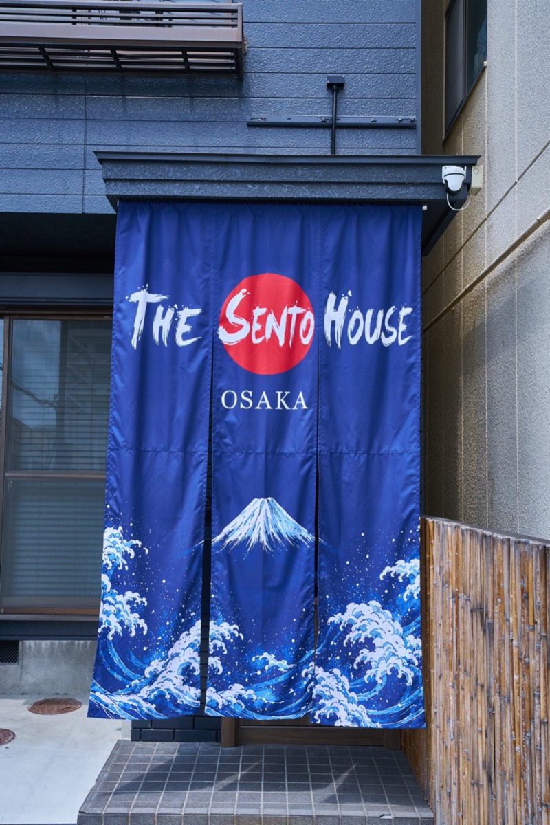 富士と大浪を染め抜いた藍色の暖簾がかかるTHE SENTO HOUSE OSAKAの外観